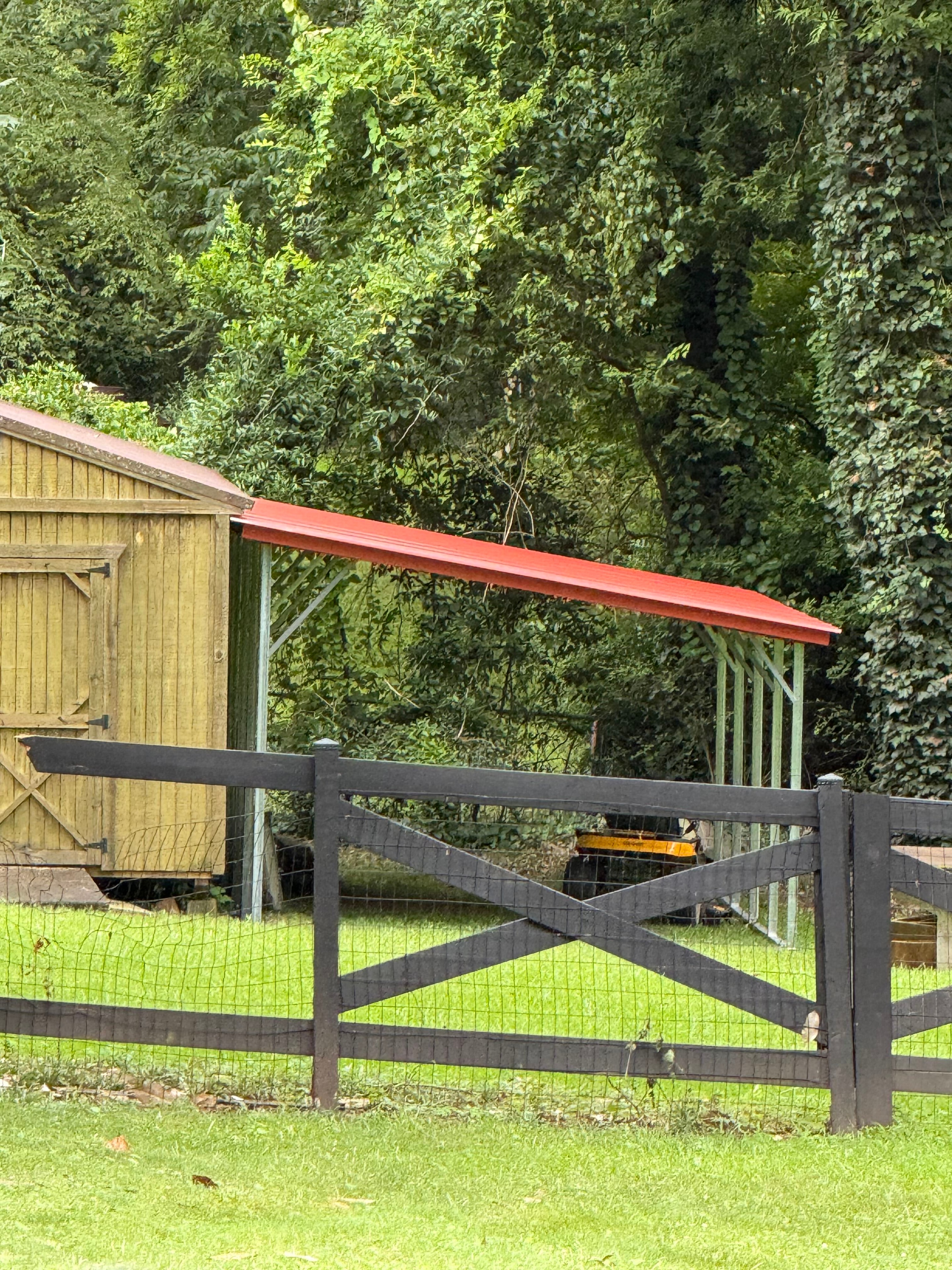 Red-roof carport beside a barn